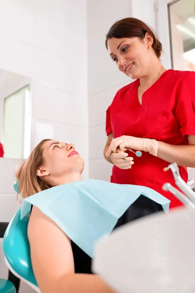 Una dentista donna esamina la cavità orale del paziente con uno strumento con uno specchio. Ritratto ravvicinato di un paziente con la bocca aperta, un medico con i guanti tiene uno specchio dentale . — Foto Stock