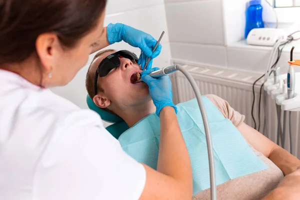 Zahnmedizin, Zahnarzt behandelt einem männlichen Patienten einen Zahn. Karies entfernen, Füllungen auf den Zähnen anbringen. — Stockfoto