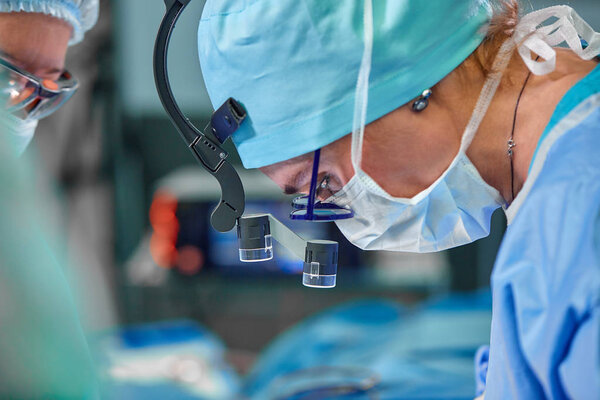 A surgeons team in uniform performs an operation on a patient at a cardiac surgery clinic. Modern medicine, a professional team of surgeons, health.