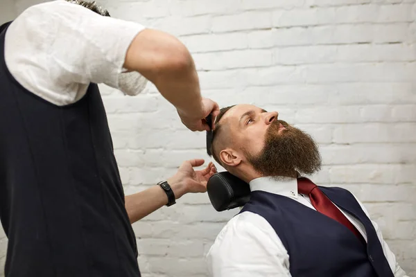 Master Barber does hairstyle and styling. Concept Barbershop. Beard styling and cut. styling of black beard. So trendy and stylish. Advertising and barber shop concept