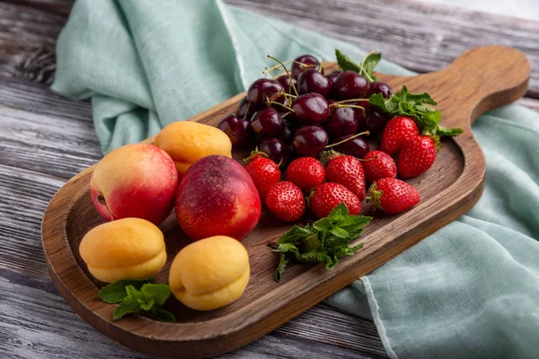 Healthy fruit platter, strawberries, apples, peaches, apricots on a dark gray wooden table, top view, close-up, selective focus.