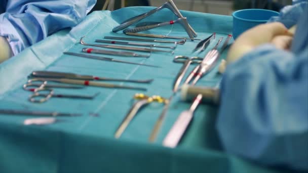 Medicina conceptual, cirugía. Mesa de operaciones con una herramienta para cirugía, primer plano, luz azul. En la mesa se extienden los instrumentos esterilizados de cirujanos, bisturíes, clips, tampones, jeringas . — Vídeo de stock