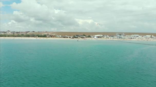 Vista panorâmica do mar e da praia em um drone voador. Tiro com golpes de câmera voando do mar para com uma infra-estrutura . — Vídeo de Stock