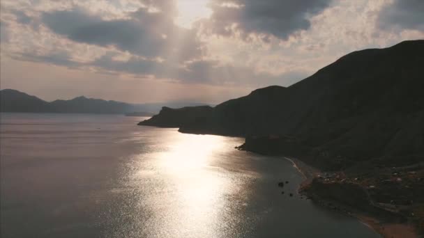 Schöne Panoramasicht auf die Berge und das Meer, gefilmt von oben. Luftaufnahmen von der Küste an einem bewölkten Tag, die Sonnenstrahlen bahnen sich ihren Weg durch die Wolken, schönes Licht — Stockvideo