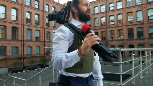 Giornalista professionista in diretta su City Street. Un reporter con abiti speciali cammina per le strade della città, sceglie luoghi per le riprese . — Video Stock