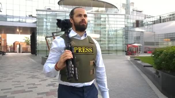 Periodista profesional vive en la calle de la ciudad. Un reportero con ropa especial camina por las calles de la ciudad, elige lugares para filmar . — Vídeos de Stock