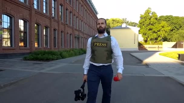 Periodista profesional vive en la calle de la ciudad. Un reportero con ropa especial camina por las calles de la ciudad, elige lugares para filmar . — Vídeos de Stock