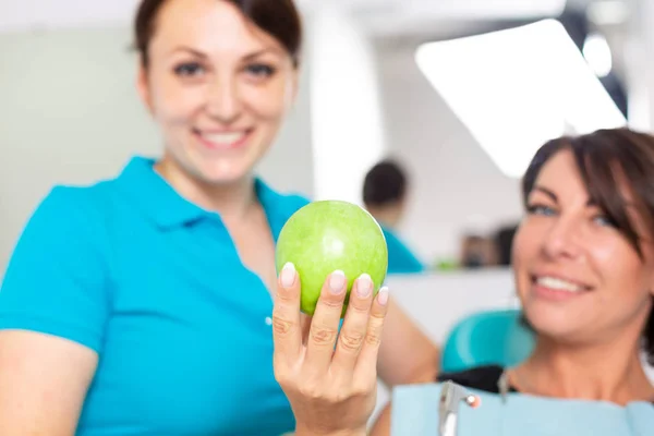 Счастливый пациент на ресепшене у стамотолога, проверяет здоровье зубов, кусает зеленый жалок. Концепция стоматологии, здоровые зубы, красивая улыбка . — стоковое фото