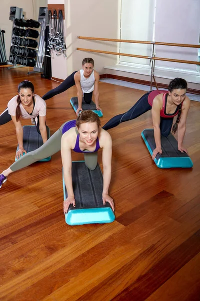 A group of sporting young people in sportswear, in a fitness room, doing push-ups or planks in the gym. Group fitness concept, group workouts, motivation