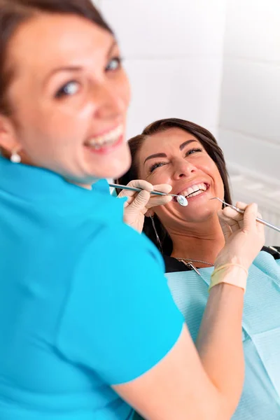 Poner aparatos dentales a los dientes de las mujeres en el consultorio dental. El dentista examina a una paciente con aparatos ortopédicos en el consultorio dental. Primer plano de una joven atractiva con aparatos ortopédicos en los dientes —  Fotos de Stock