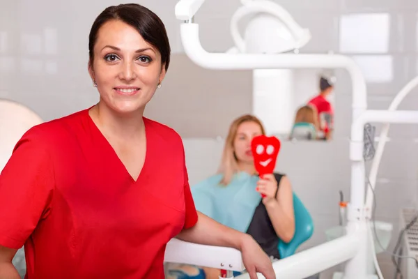 Dentist doctor poses for the camera on the background of the dental office with the patient. Concept healthy teeth, beauty, health.