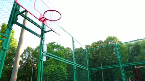 Il giocatore di basket si allena giocando a basket all'aria aperta. Un giovane uomo si allena saltando con un pallone da basket per colpire l'anello. Motivazione sportiva, allenamento all'aperto . — Video Stock