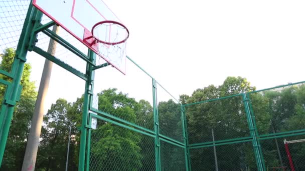 Basketspelare tränar att spela basket i det fria. En ung man tränar hoppa med en basketboll för att träffa ringen. Sport motivation, träning utomhus. — Stockvideo