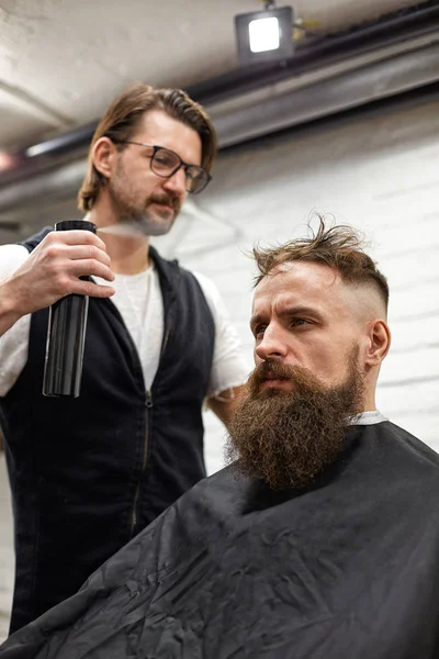 Meister schneidet Männern Haare und Bart im Friseursalon, Friseur frisiert jungen Mann — Stockfoto