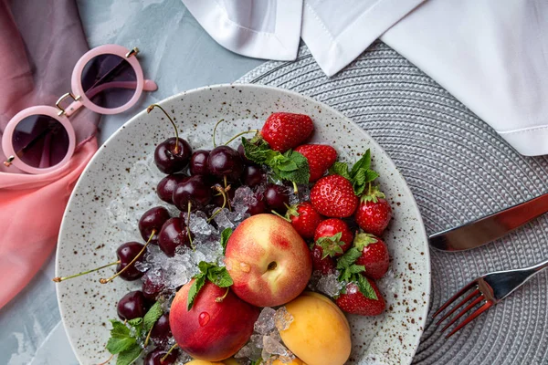 Healthy fruit platter, strawberries, apples, peaches, apricots on a dark gray wooden table, top view, close-up, selective focus.