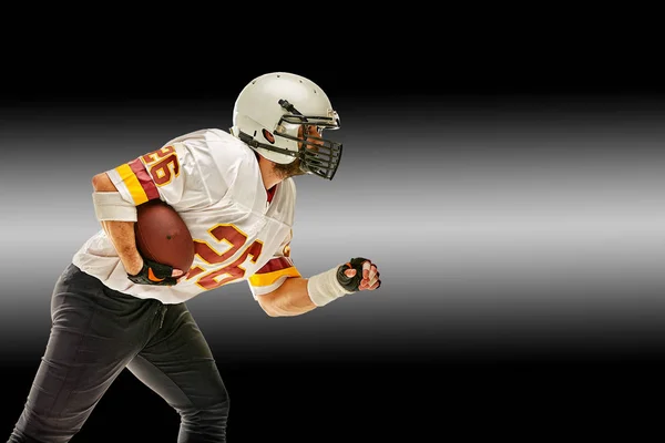 American football player in motion with the ball on a black background with a light line, copy space. The concept of the game is American football, movement. Black white background, copy space. sport