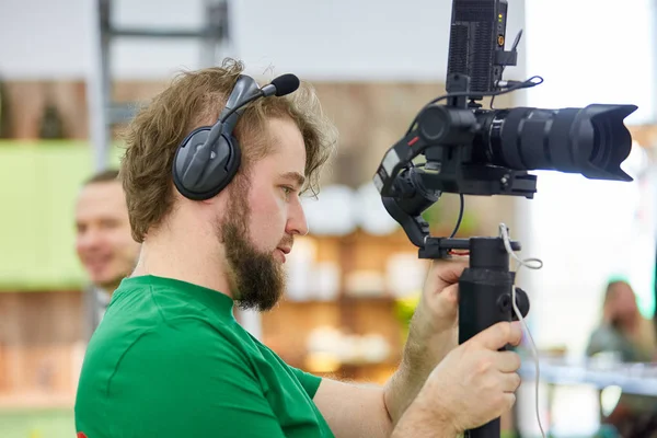 Videographer shooting a film or a television program in a studio with a professional camera, backstage — Stock Photo, Image