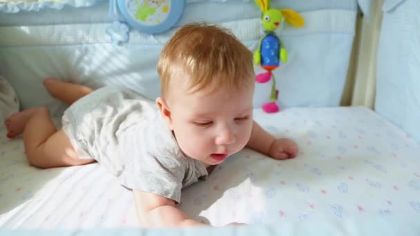 婴儿床上的小宝宝笑着试图爬行。快乐的童年，幼稚的快乐，人生的第一步. — 图库视频影像