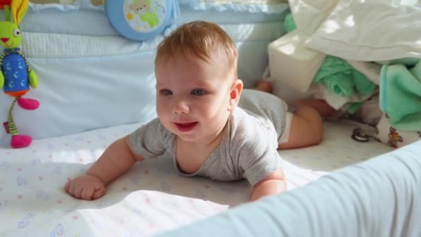 婴儿床上的小宝宝笑着试图爬行。快乐的童年，幼稚的快乐，人生的第一步. — 图库视频影像