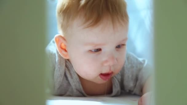 A close-up of a little toddler in a crib laughing and trying to crawl. Happy childhood, childish joy, the first steps in life. — Stock Video