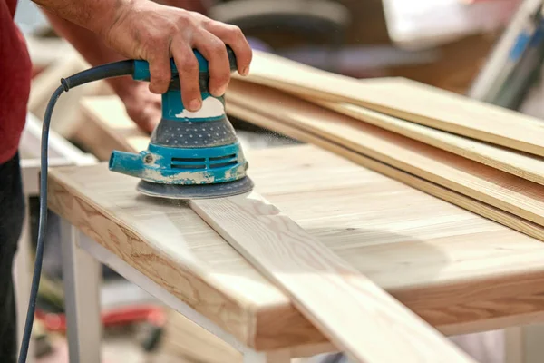 Grinder worker polishes a wooden board. Sanding boards Orbital eccentric machine. — Stock Photo, Image