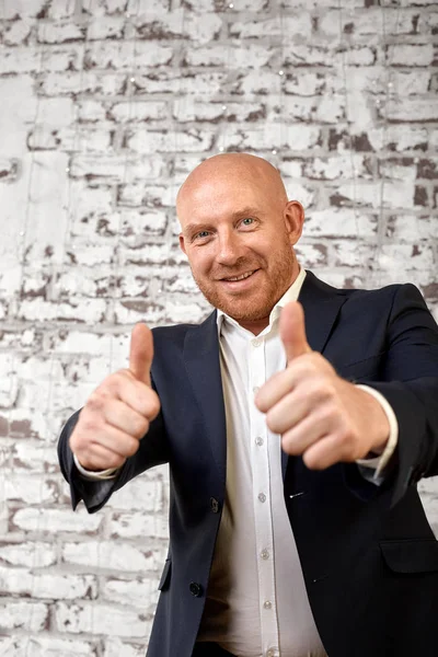 Successful male bald businessman poses for the camera and shows class with his hands. Successful business personality development.