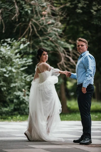 Vista trasera de una pareja recién casada abrazándose en un parque. Pareja va en la distancia . — Foto de Stock