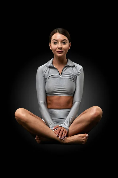 Schöne sportliche Fitness-Mädchen beim Yoga sitzend in Lotusposition auf dunklem Hintergrund. Yoga-Konzept, gesunder Lebensstil, Einheit von Körper und Geist — Stockfoto