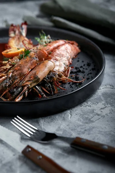 Grilled king prawns, with tomato sauce on a gray background, low key. Series concrete background. Food concept, food style, Copy space, food advertising for magazines and social networks.