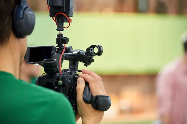 Na pozadí natáčení filmů nebo videoproduktů. Obsluha s fotoaparátem na sadě vybere stříleču. — Stock fotografie