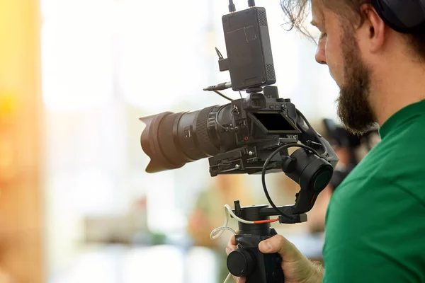 Na pozadí natáčení filmů nebo videoproduktů. Obsluha s fotoaparátem na sadě vybere stříleču. — Stock fotografie