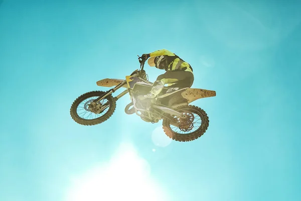 Pilota su moto dirtbike motocross cross-country in volo, salta e decolla sul trampolino contro il cielo. Concetto riposo estremo attivo . — Foto Stock