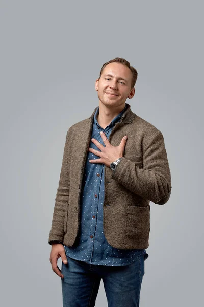 Smiling old casual man in leather jacket with a good-natured face standing against gray studio wall — Stock Photo, Image