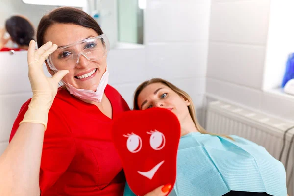 Zahnärztin zeigt ihren Patienten neue Zähne durch den Spiegel im Zahnkabinett. Patient ist zufrieden — Stockfoto