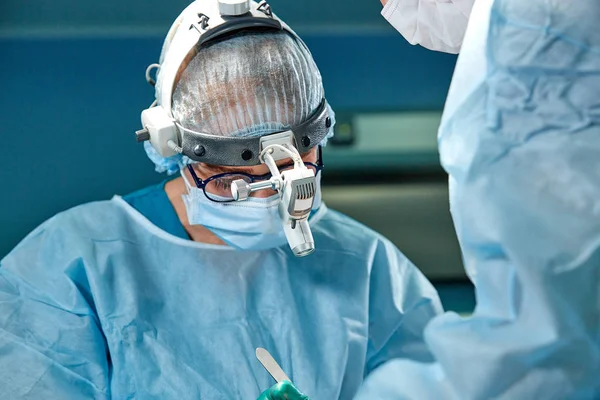 Close up portrait of female surgeon doctor wearing protective mask and hat during the operation. Healthcare, medical education, surgery concept. — Stock Photo, Image