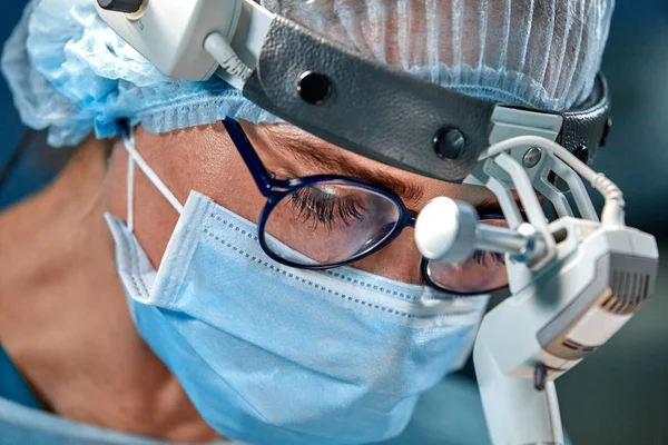 Närbild porträtt av kvinnliga kirurgen läkare bär skyddande mask och hatt under operationen. Sjukvård, medicinsk utbildning, kirurgi koncept. — Stockfoto