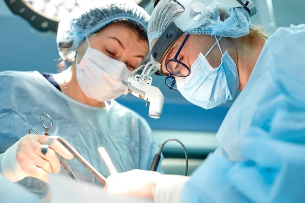 Retrato del equipo de cirujanos multiétnicos trabajando en un quirófano. Varios médicos que rodean al paciente en la mesa de operaciones durante su trabajo. Cirujanos de equipo trabajando en quirófano . — Foto de Stock