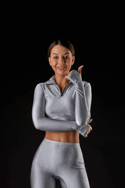 Sexy brunette girl with a slim figure in leggings posing in studio on a black background — Stock Photo, Image