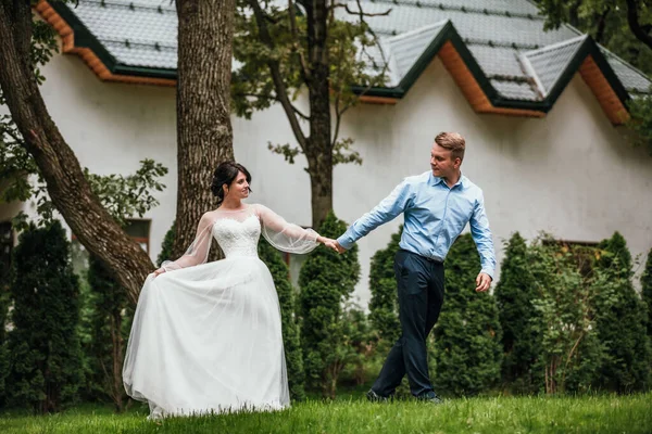 結婚式で花嫁と新郎春の自然を屋外で歩く日。ブライダルカップル、幸せな新婚の女性と男は緑の公園で受け入れる。結婚式のカップルの屋外が大好きです。花嫁と新郎 — ストック写真