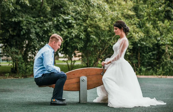 Novia y novio están sentados en un columpio en un día soleado en el parque — Foto de Stock