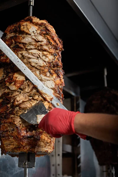 Rostat kött på benet för beredning av donatorer eller shawarma. Närbild. Kocken skär köttet stekt över träkol för beredning av shawarma i pita bröd.Närbild — Stockfoto