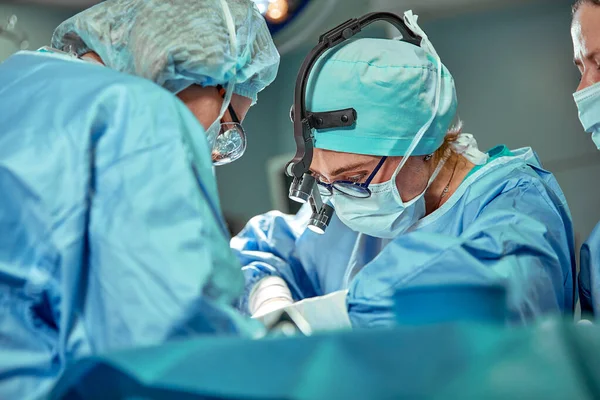 Groupe de chirurgiens regardant le patient sur la table d'opération pendant leur travail — Photo