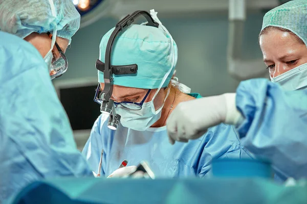 Gruppe von Chirurgen betrachtet den Patienten während seiner Arbeit auf dem Operationstisch Stockbild