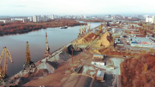 Gruas portuárias na margem do rio produzem areia. Guindastes portuários com um balde na margem do rio. Extração de areia do rio. Guindastes de carga portuária extrai areia do rio, produção. Pôr do sol. Barcaças . — Vídeo de Stock