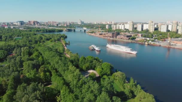 Bellissimo paesaggio con una nave bianca che naviga lungo il fiume vicino a ripide rive ricoperte di verde foresta. Filmati delle scorte. Nave bianca che si muove contro il cielo grigio nuvoloso, concetto di trasporto fluviale . — Video Stock