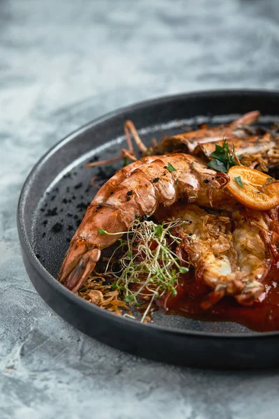 Grilled king prawns, with tomato sauce on a gray background, low key. Series concrete background. Food concept, food style, Copy space, food advertising for magazines and social networks.