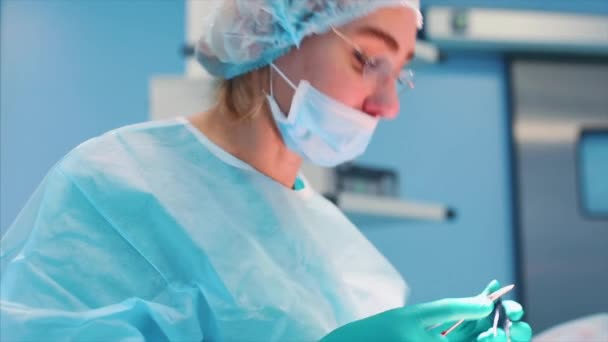 Dokter bedah wanita di ruang operasi dengan refleksi kacamata. ruang operasi cahaya biru, operasi rhinoplasty untuk meningkatkan estetika hidung. Medetsina, operasi plastik . — Stok Video
