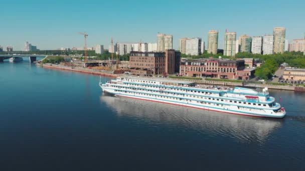 Hermoso paisaje con un barco blanco navegando a lo largo del río cerca de las empinadas orillas cubiertas de bosque verde. Imágenes de archivo. Barco blanco moviéndose contra el cielo gris nublado, concepto de transporte fluvial . — Vídeos de Stock