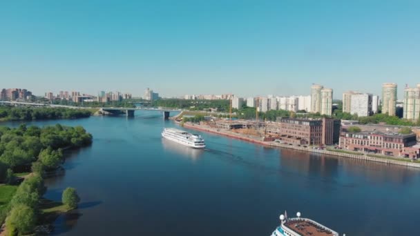 Prachtig landschap met een wit schip zeilen langs de rivier in de buurt van steile oevers bedekt met groen bos. Stock footage. Wit vat in beweging tegen grijze bewolkte hemel, rivier transport concept. — Stockvideo