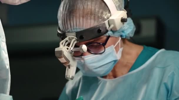 Cerrahlardan oluşan bir ekibin ameliyat sırasında büyük bir planı vardır, mavi ışıklı bir ameliyathane, burun estetiğini geliştirmek için bir burun estetiği operasyonu. Medetsina, estetik ameliyat. — Stok video